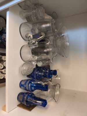 Des bouteilles et des verres sont empilés sur une étagère dans une cuisine.