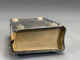 an old book sitting on top of a table next to a silver object