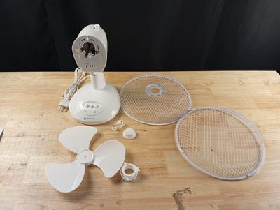 une table sur laquelle se trouvent un ventilateur, une raquette de tennis et d'autres objets