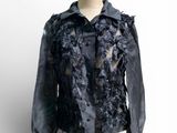 une veste noire ornée de fleurs noires, posée sur un mannequin
