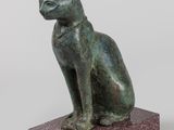 statue d'un chat assis sur un socle, sur fond blanc
