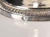 a silver plate with a diamond on it on a table