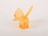 une bougie orange surmontée d'un papillon, posée sur une surface blanche