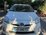 une Toyota Prius blanche garée devant une maison