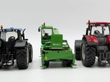 three toy tractors are shown side by side on a white surface