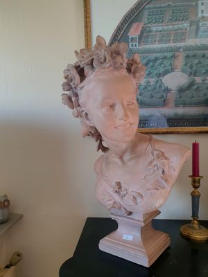 un buste de femme posé sur une table, à côté d'une bougie