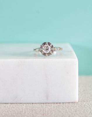 un gros plan d'une bague en diamant posée sur un bloc de marbre