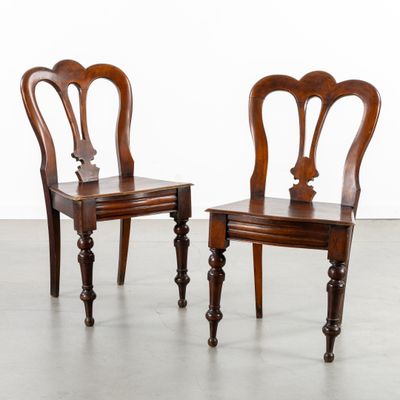 two wooden chairs sitting next to each other on top of a cement floor