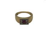 gros plan d'une bague en or avec une pierre rouge