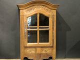 une vieille armoire en bois avec une porte vitrée, posée sur un parquet