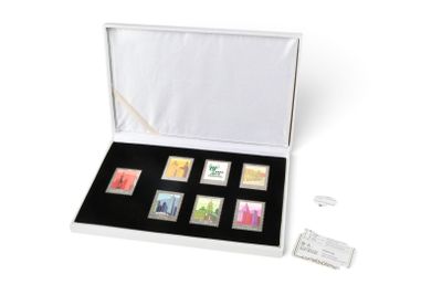 une boîte blanche contenant six timbres, posée sur une surface blanche