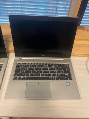 two laptops are sitting on a desk near a window