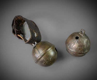 une paire de clochettes en bronze munies d'une lanière en cuir de chaque côté