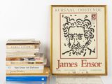 a picture of a picture of james ensor next to a pile of books