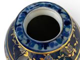 a blue and gold vase on a white surface