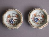 pair of porcelain bowls with a coat of arms and a coat of arms on them