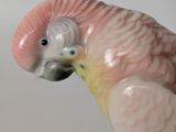 a figurine of a pink and yellow parrot on a branch