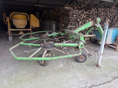 un tracteur équipé d'une charrue, devant un tas de bois