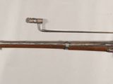 an old gun mounted on a wall next to a white wall