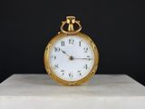 une montre de poche en or posée sur un bloc de marbre
