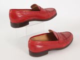 pair of red leather loafers on clear acrylic stand on white background