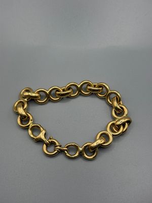 gros plan d'un bracelet en chaîne en or sur une surface grise