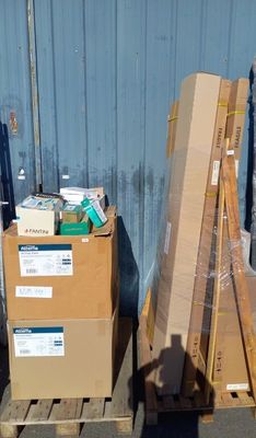 une pile de cartons posée sur une palette devant un bâtiment