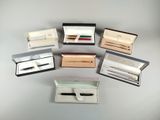 six different pens and a pen in a box on a table