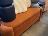 an orange couch with pillows on top of it in a room