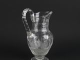 a clear glass pitcher with a handle on a black background