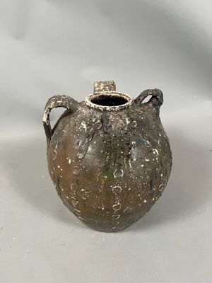 a brown vase with a handle on a white surface