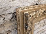 a picture of a gold frame on a stone wall