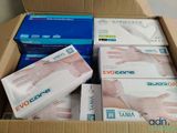 plusieurs boîtes de gants dans un carton posé par terre