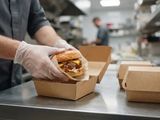 un homme qui tient un hamburger dans une boîte