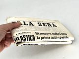 someone is holding a newspaper in their hand on a white surface