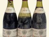 trois bouteilles de vin rouge sont posées les unes à côté des autres sur une surface blanche