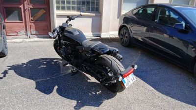une moto noire garée sur un parking à côté d'une voiture bleue