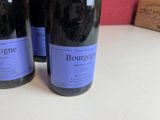 three bottles of wine sitting on a counter top next to a box of boxes