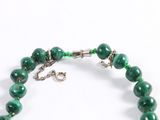a close up of a bracelet with green beads on a white background