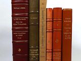 several books are stacked on top of each other on a white surface