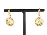 a pair of gold earrings on a black stand