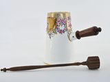 a white vase with a wooden handle next to a wooden spoon