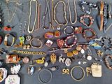 many different types of necklaces and bracelets laid out on a table