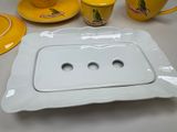 a white plate with three holes on it next to a yellow cup and saucer