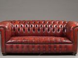 a red leather chesterfield sofa on a grey background
