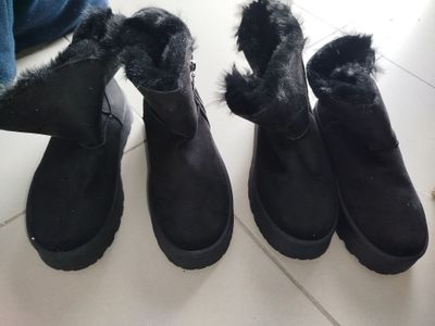 trois paires de bottes noires sont alignées sur le sol