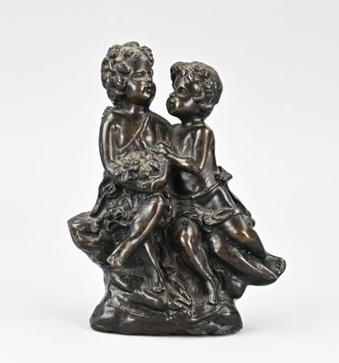 a bronze statue of two children sitting on a rock