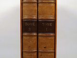 two books are stacked on top of each other on a white surface