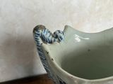 a small bird sitting on top of a blue and white vase