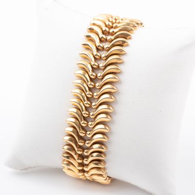 gros plan d'un bracelet en or sur un oreiller blanc